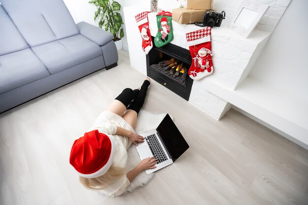 El mundo entero en un solo toque. Primer plano de la hermosa joven mujer de cabello rubio trabajando en la computadora portátil y sonriendo fondo de Navidad