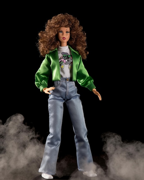 Una muñeca barbie con una chaqueta verde y jeans azules se yergue en humo.