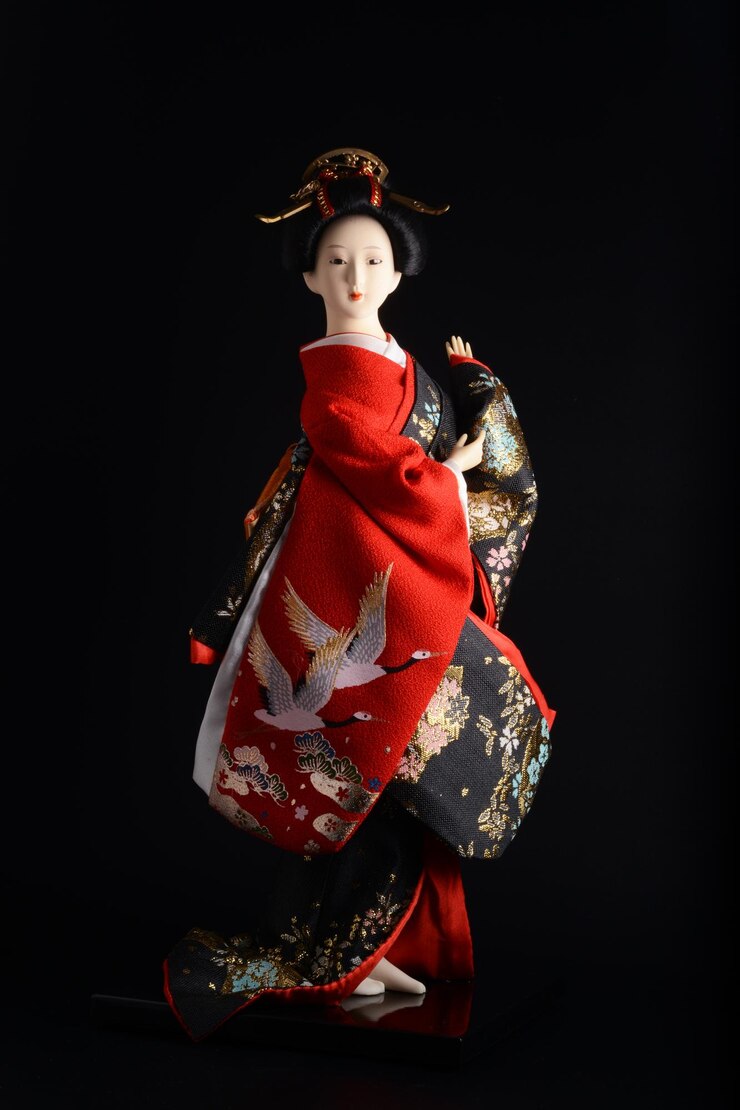 Muñeca geisha japonesa vestida con un hermoso kimono sobre un fondo negro