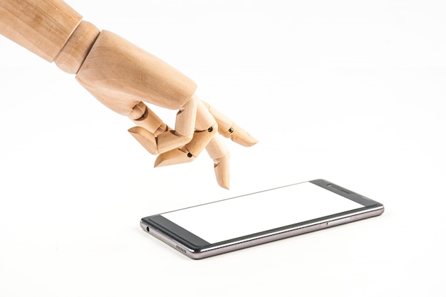 Foto muñeca de mano de madera tocando un teléfono inteligente sobre fondo blanco.