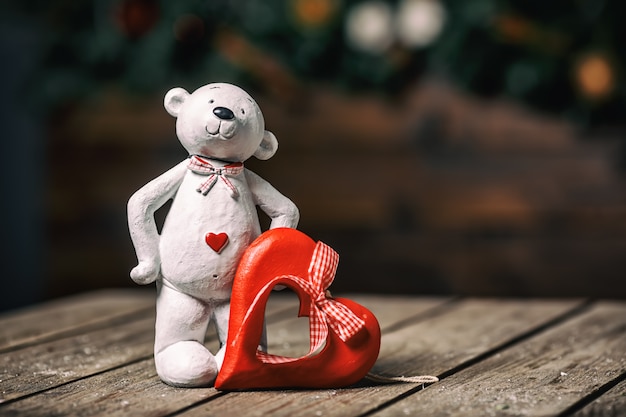 Muñeca de oso blanco con corazón de pie sobre fondo de madera vieja. Concepto de San Valentín.