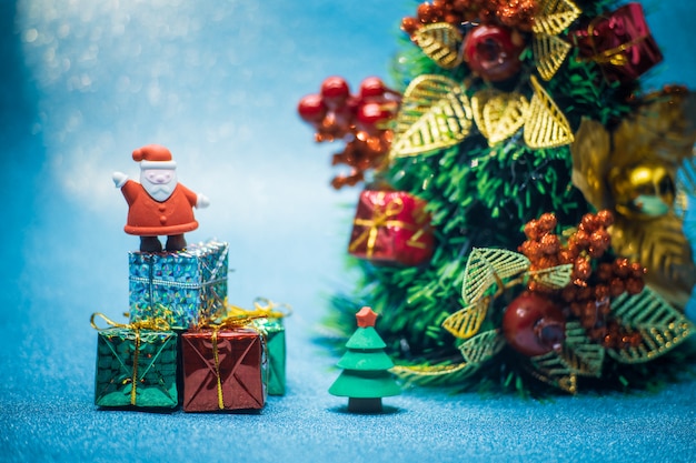 Muñecas de Santa Claus y árbol de Navidad y caja de regalo en la nieve