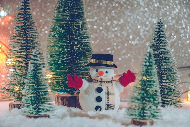 Muñeco de nieve con árbol de Navidad y adornos. Fondo de brillo