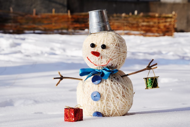 Muñeco de nieve con un cubo en la cabeza sobre un fondo de nieve