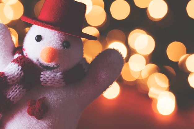 Muñeco de nieve festivo con sombrero y bufanda contra luces de hadas bokeh borrosas