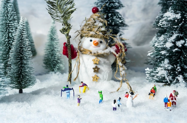 Muñeco de nieve y gente en bosques de pinos durante el invierno