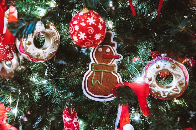 Muñeco de nieve de Navidad, bolas rojas, donas y adornos colgando del árbol de Navidad. Decoración festiva en el interior. Detalles y atmósfera de año nuevo