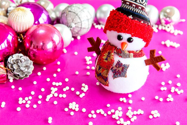 Muñeco de nieve navideño en decoración navideña con fondo rosa