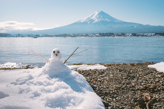 Muñeco de nieve de pie en el paisaje de invierno en Fuji montaña de fondo en el lago kawaguchiko, Japón