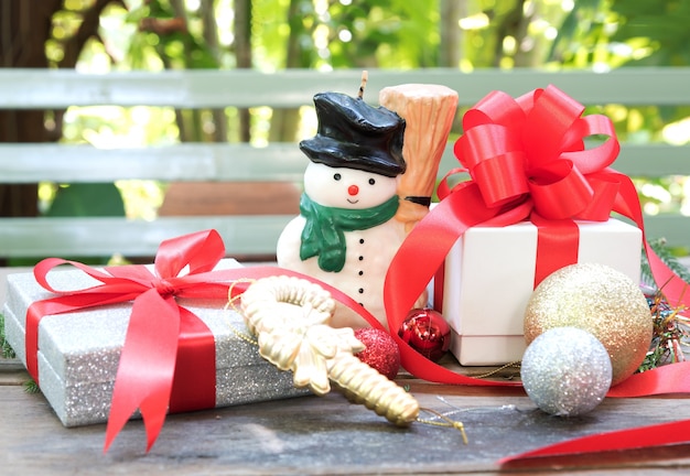 Foto muñeco de nieve, regalo de navidad y ornamento sobre la mesa de madera