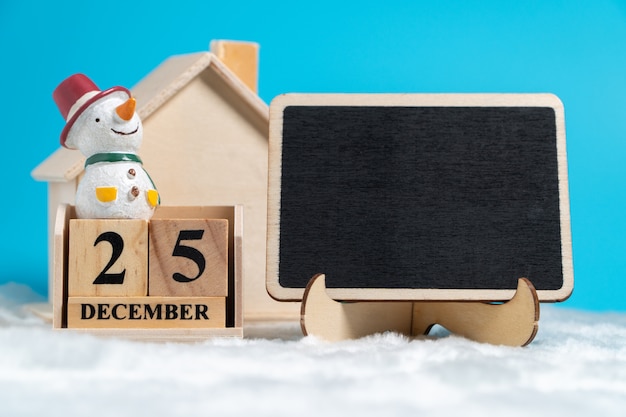 Muñeco de nieve sentado en el calendario de bloque de madera establecido el 25 de diciembre