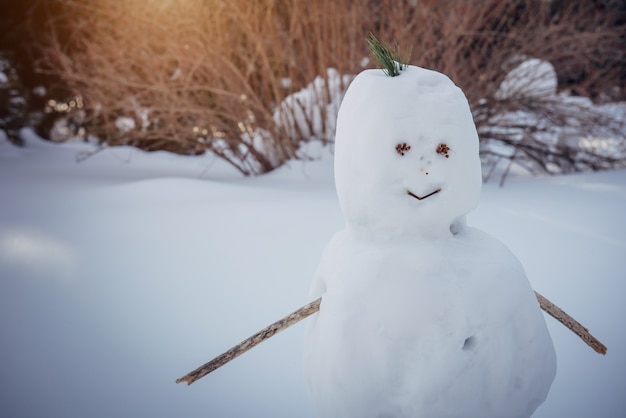 Muñeco de nieve sobre un fondo blanco borroso, primer plano. Invierno, año nuevo, juegos al aire libre. Copie el espacio.