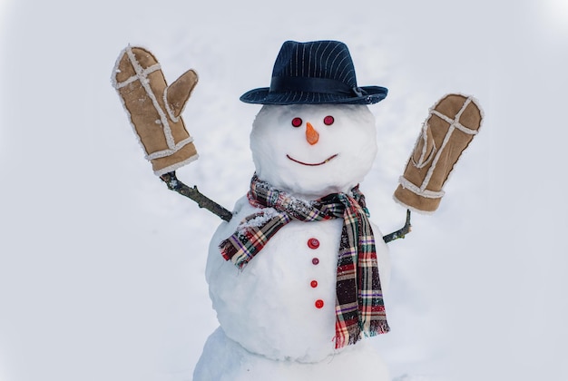 Muñeco de nieve con sombrero y bufanda en invierno muñeco de nieve al aire libre y concepto de Navidad día de nieve