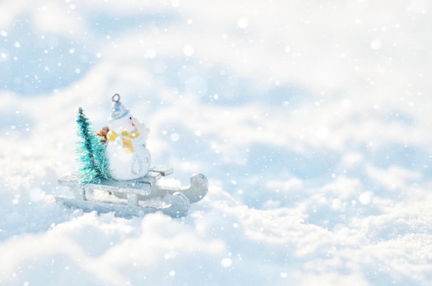 Muñeco de nieve en un trineo con un árbol de Navidad en ventisqueros Fondo de temporada de invierno