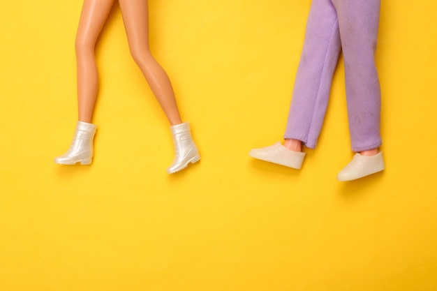 Muñeco piernas masculinas y femeninas en zapatos sobre fondo amarillo Diseño minimalista creativo