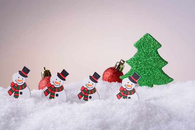 Muñecos de nieve de adorno de Navidad, árbol de Navidad y bolas rojas en la nieve