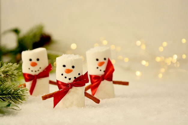 Muñecos de nieve de malvavisco Navidad con ramas de abeto y bokeh