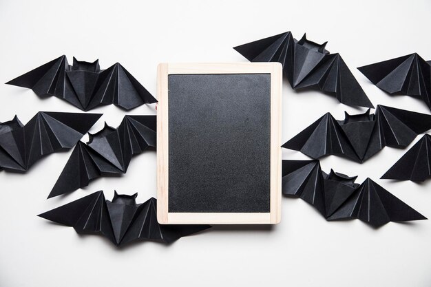 Murciélagos de drácula de papel de origami de Halloween con una pizarra en blanco