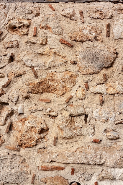 Muro antigo de pedras grandes e pequenas dentro de argamassa de cimento Foto vertical