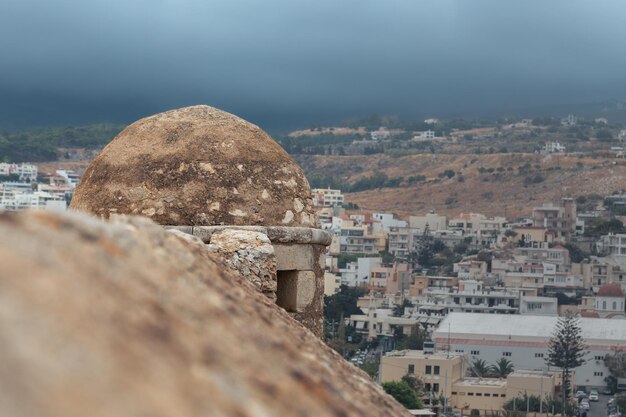 Muro de pedra e pequena torre da fortaleza veneziana Fortezza com cidade ao fundo Rethymno Grécia