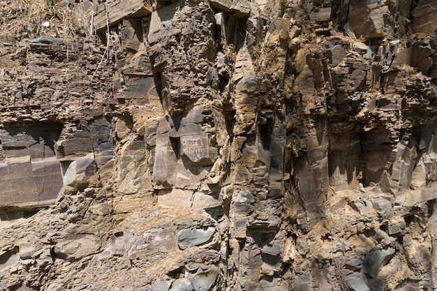 Muro de granito. Primer plano de una parte de la roca destruida por el tiempo. Piedras de color gris oscuro. foto de alta calidad