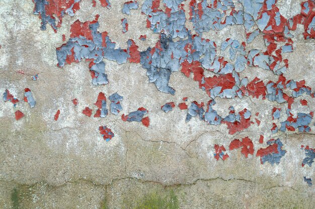 Muro de hormigón coloreado antiguo. Pared desgastada con pintura azul y roja desconchada.
