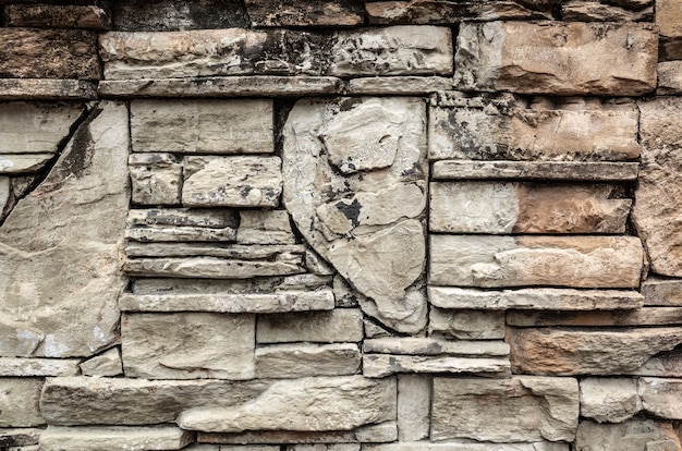 Muro de piedra apilada en fondo de color marrón envejecido