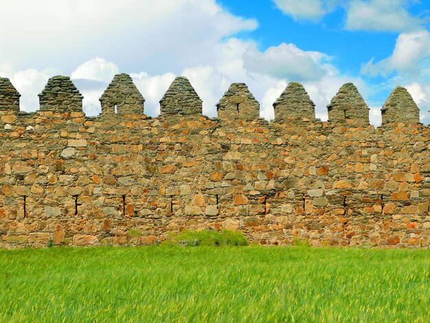 Un muro de piedra en un campo con un cielo azul detrás