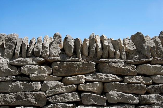 Muro de piedra seca y fondo de cielo azul con espacio para texto