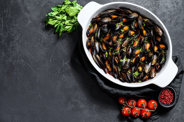 Muscheln in Tomatensauce mit Petersilie und Kräutern. Schwarzer Hintergrund. Draufsicht. Platz für Text