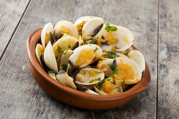Muscheln mit Marinerasoße Spanisches Rezept Almejas a la Marinera auf Holztisch