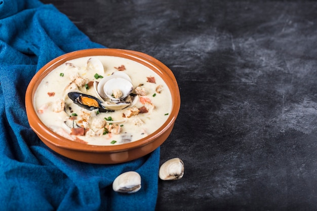 Muschelsuppe in einem braunen Teller. Die Hauptzutaten sind Schalentiere, Brühe, Butter, Kartoffeln und Zwiebeln.