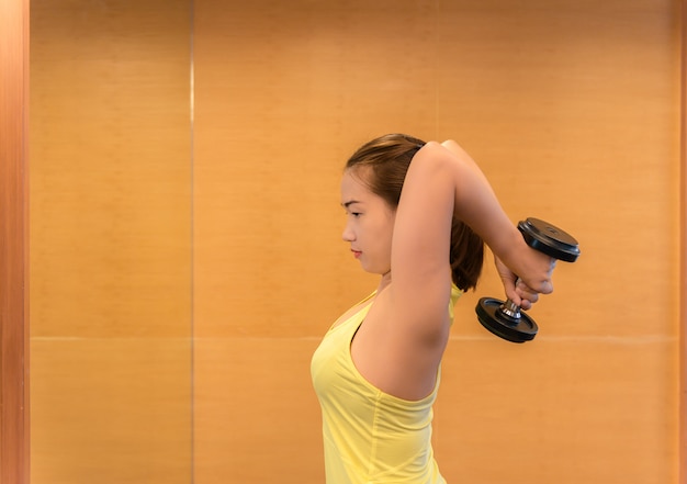 Musculação. Mulher forte do ajuste que exercita com pesos.