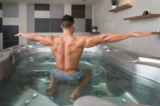 Muscular Fitness Bodybuilder haciendo ejercicio de peso pesado para bíceps en máquina con cable en el gimnasio