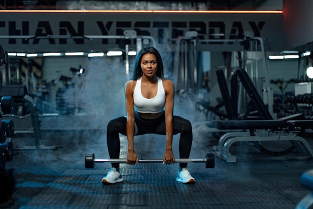 Muscular jovem fitness esportista mulher treino com barra no ginásio de fitness