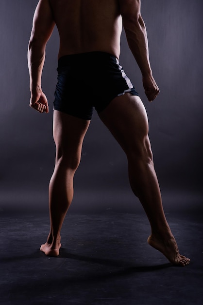 Foto musculares piernas masculinas de cerca foto de estudio fondo oscuro