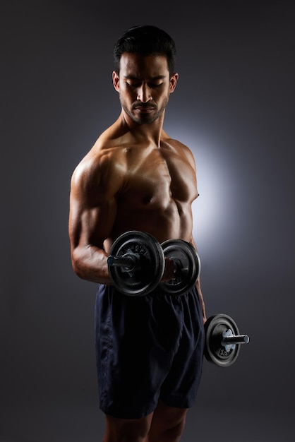 Músculo forte e homem de estúdio com desafio de haltere resulta desenvolvimento de treino de braço e progresso de aptidão corporal Equipamento de ginástica de sombra escura e atleta esportivo com foco de treinamento em fundo cinza
