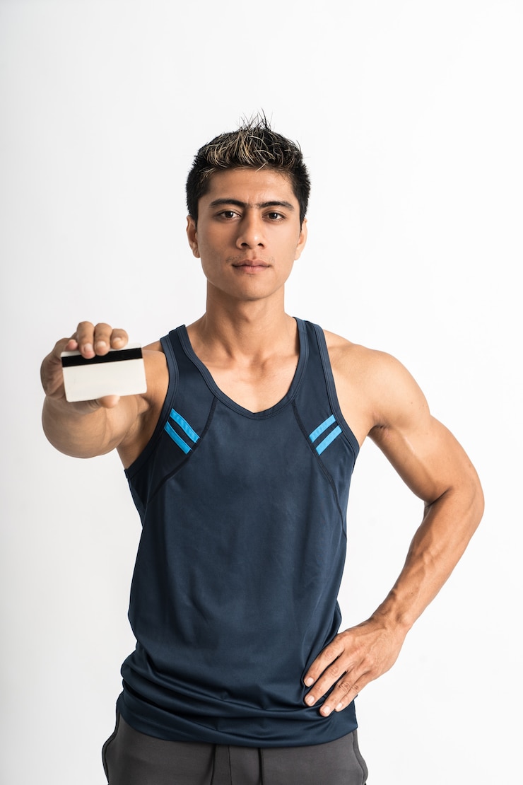 Foto músculo joven vistiendo ropa deportiva de pie mirando hacia adelante con la tarjeta de crédito actual en su mano