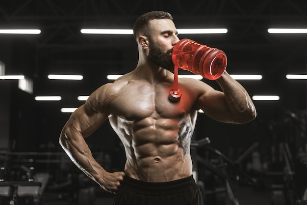 Músculos atléticos fuertes y guapos hombres beben agua y nutrición deportiva entrenamiento concepto de culturismo