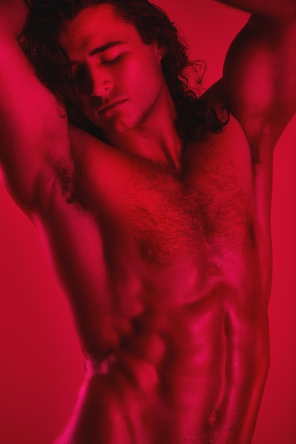 Músculos impresionantes Foto de estudio de un joven musculoso posando sin camisa contra un fondo rojo