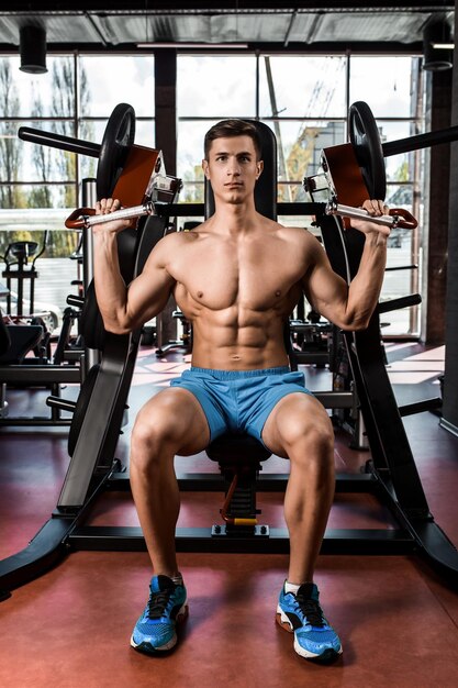 Los músculos tensos de las manos bajo carga. Hombre haciendo ejercicio para los bíceps en el gimnasio. Trabajar en los músculos de la palanca en el simulador. Fotos para revistas deportivas, carteles y sitios web.