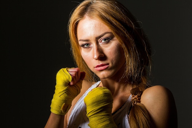 Musculosa jovem desportista atlética em roupas esportivas com bandas ou luvas na academia em um fundo escuro Artes marciais esportivas Copie o espaço para anúncios de equipamentos esportivos de nutrição fitness ou exercício