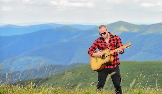 Música acústica. caminhante músico encontra inspiração nas montanhas. mantenha a calma e toque guitarra. homem com guitarra no topo da montanha. música para a alma. ouvindo música. som de liberdade. em uníssono com a natureza.