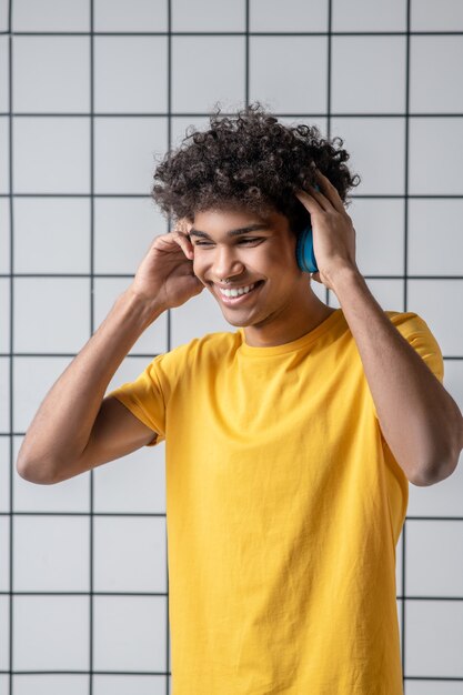 Música. Chico joven afroamericano en auriculares sonriendo y mirando contento