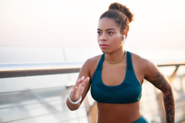 Música y correr. Joven afroamericana con auriculares escuchando música y corriendo