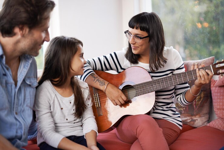 Foto música da mãe e tocar guitarra para a família em casa relaxando e desfrutando juntos no sofá performance pai e filho com mulher na sala de estar entretenimento e feliz com instrumento musical