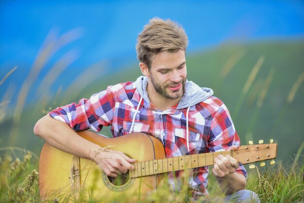 Música de caminhada homem músico com guitarra no topo da montanha músico inspirado músico hipster ambiente inspirador festival de música de verão ao ar livre silêncio das montanhas e som das cordas da guitarra