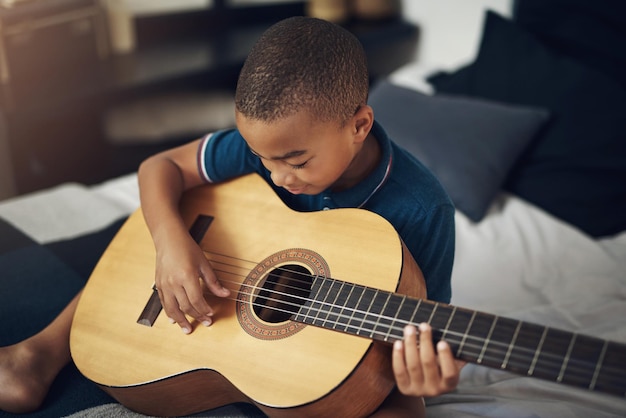 La música estimula todas las funciones importantes de nuestro cerebro Fotografía de un niño tocando la guitarra en casa