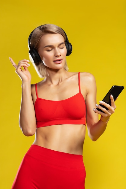 Música fazendo sua garota feliz linda fitness em fones de ouvido, mantendo os olhos fechados e ouvindo música