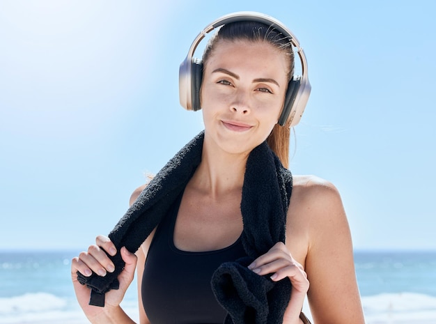 Música de fitness y retrato de mujer en la playa para entrenamiento y salud Relájese con radio y toalla con una chica y auriculares después de hacer ejercicio para deportes energéticos y objetivos por la mañana junto al mar